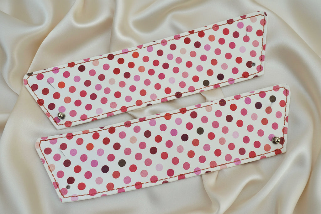 Paire de manchettes ouhoui en cuir blanc à pois rose, rouge et framboise avec leur fermeture par bouton de col mais sans les bouton de manchettes.